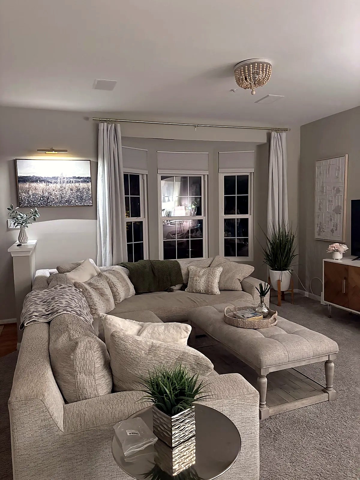 Family room with a curved sectional and bay windows at dusk