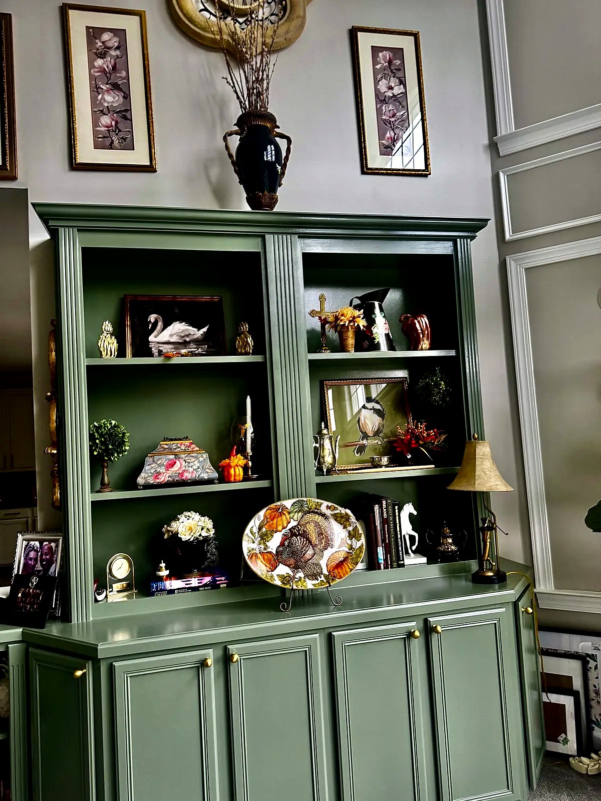 Sage green built-in bookcase styled with artwork and accessories