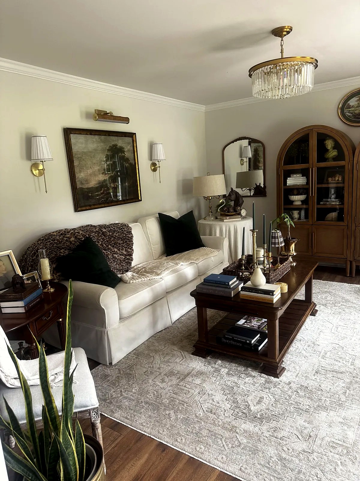 Living room with a cream sofa, green pillows and a crystal chandelier