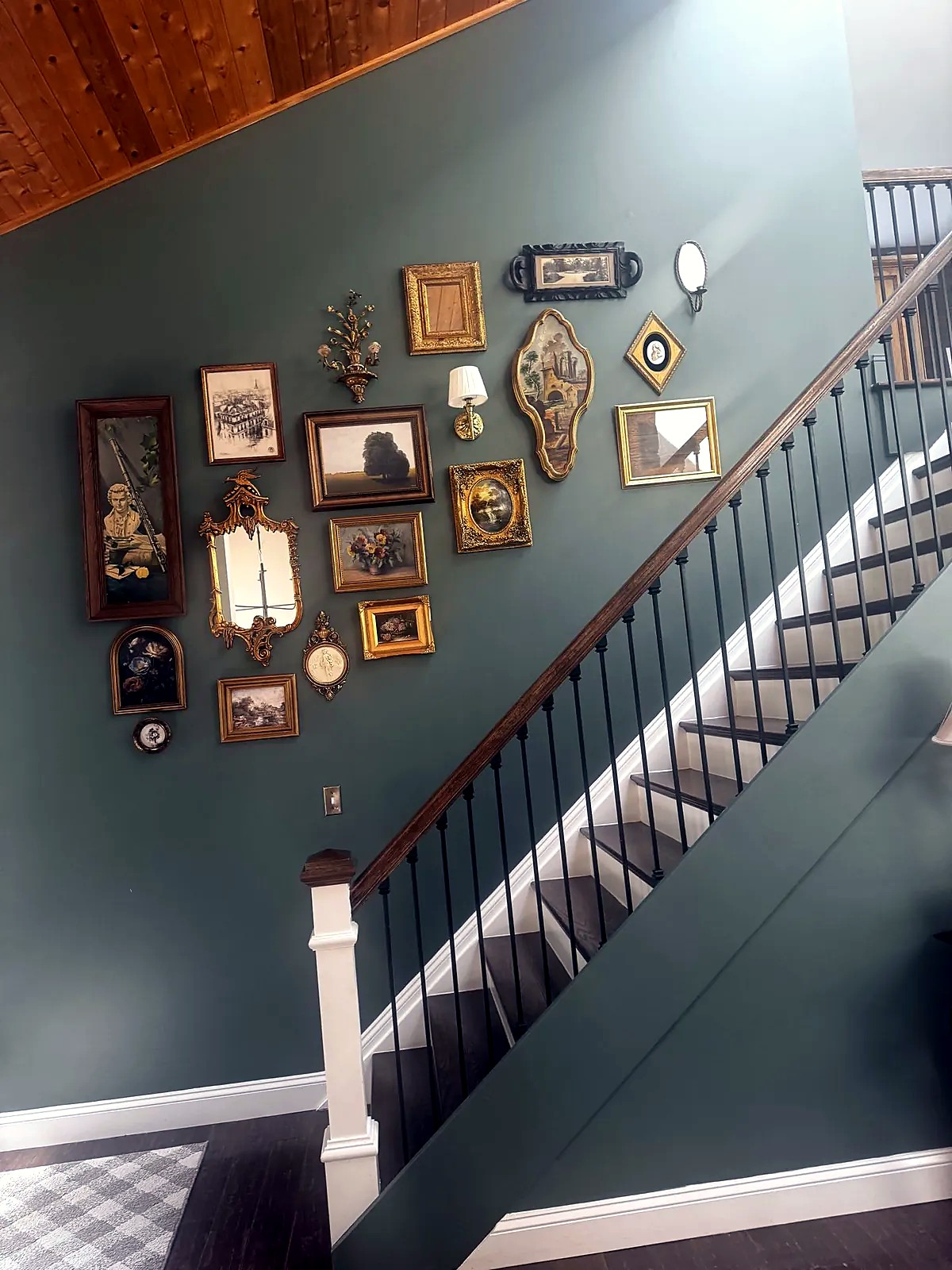 Green staircase with a gallery wall of framed art and mirrors